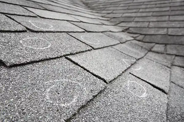 Close up of damaged asphalt shingles with curling and wear